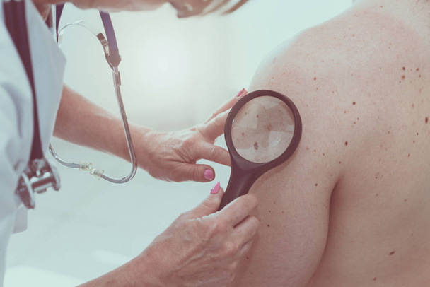 Dermatologist examining the skin of a patient - Photo, Image