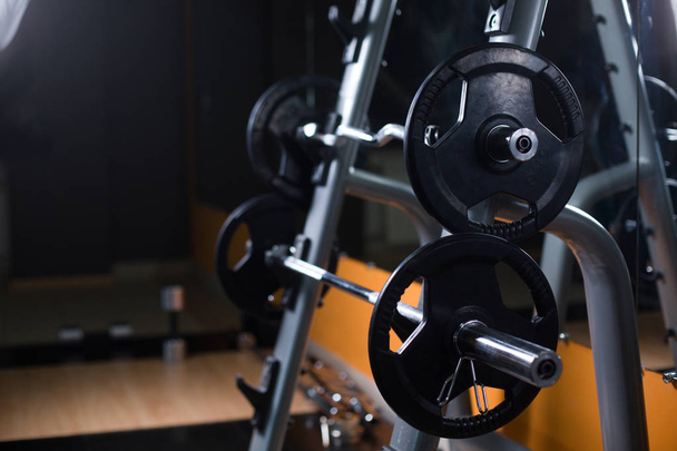Two long barbells on a stand. Barbell holder on a blurred gym background. Heavy, huge black dumbbells. Sport equipment. - Foto, Imagem