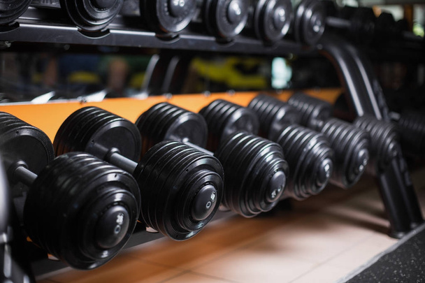 A set of barbells on a gym background. Black metal heavy dumbbells on shells. Bodybuilding, physical training concept. - Foto, Imagem