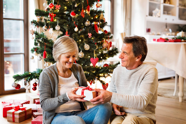 Senior couple in front of Christmas tree with presents. - Foto, Imagem