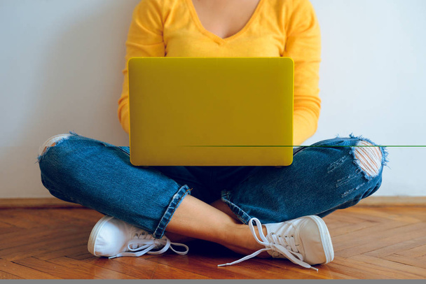 Nuori kaunis nainen istuu lattialla kannettavan tietokoneen kanssa
 - Valokuva, kuva