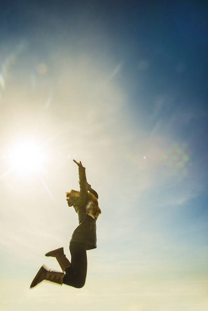 Foto van mooi meisje springen met verhoogde omhoog handen op besneeuwde berg - Foto, afbeelding