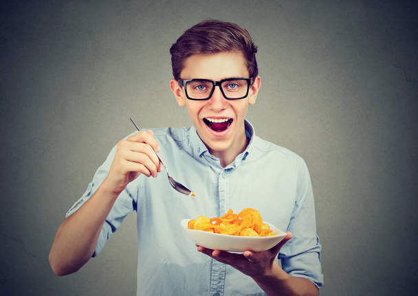 Young funny man having a plate of potato chips - 写真・画像