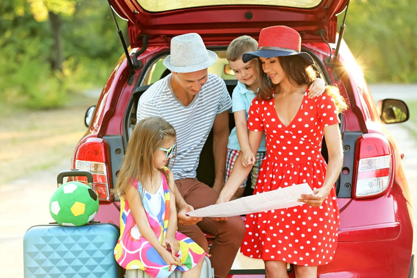 Happy family looking at map next to car in countryside - 写真・画像