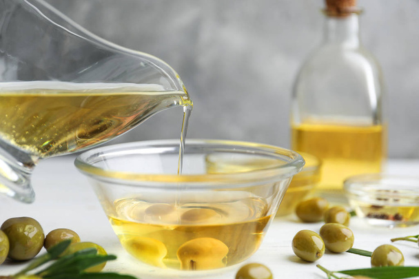 Pouring natural olive oil into glass bowl  - Fotografie, Obrázek