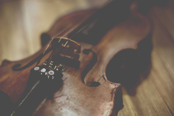 Old violin lying on a wooden surface - 写真・画像