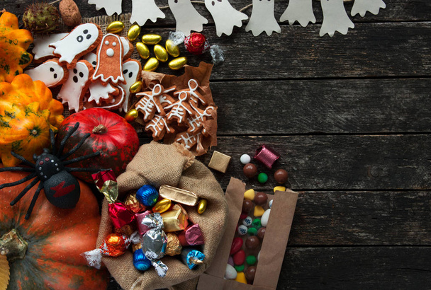 Happy Halloween card. Funny delicious ginger cookie, bag of sweets and candies shape ghost and skeleton with pumpkins and sweets. - Foto, Bild