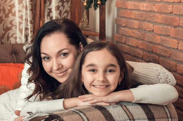 Two beautiful girls, mother and daughter siting on a sofa in Chr - Photo, Image