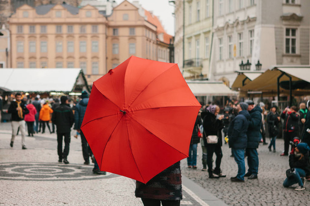 Ένας οδηγός με μια παραδοσιακή κόκκινη ομπρέλα στην πλατεία της παλιάς πόλης στην Πράγα καλεί τους τουρίστες να επισκεφθούν τα αξιοθέατα. Τουρισμού σε Χριστούγεννα. Δημοκρατία της Τσεχίας. Ευρώπη. - Φωτογραφία, εικόνα