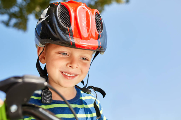 Boy in helmet standing with bike at autumn park - Foto, Imagen