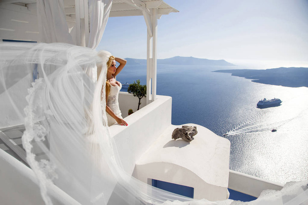 Linda modelo loira feminina com um corpo perfeito e cabelo longo incrível na ilha de Santorini, na Grécia e em torno dele é uma vista incrível
 - Foto, Imagem