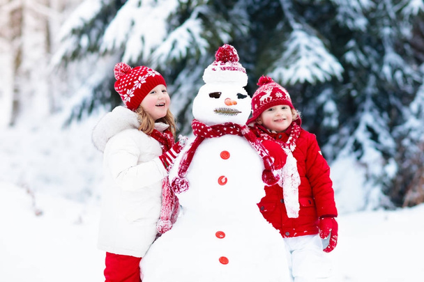 Lapset rakentavat lumiukkoa. Lapset lumessa. Talvi hauskaa
. - Valokuva, kuva