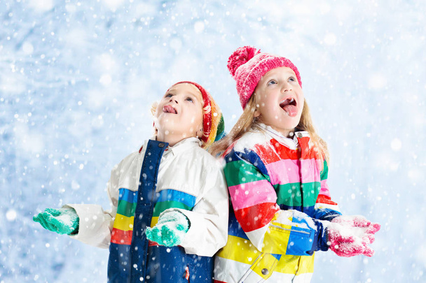 Děti hrají ve sněhu. Děti hrají venku v zimě sněžení. - Fotografie, Obrázek