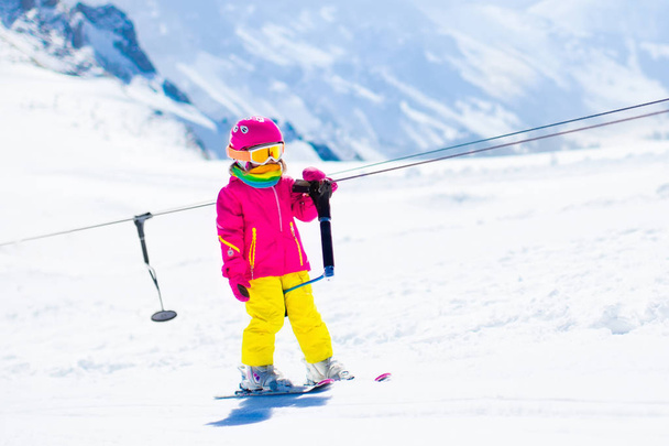 Ребенок на лыжном подъемнике в зимних горах
 - Фото, изображение