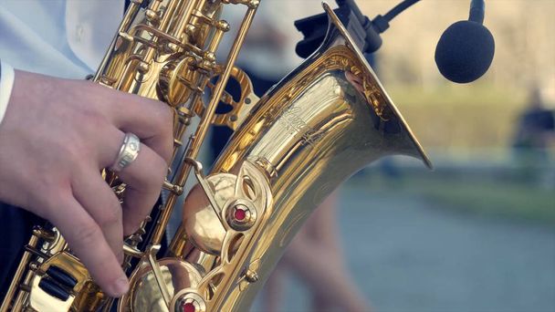 Hands of groom play on saxophone. Closeup hands of man playing golden alto saxophone with light effect. Men playing saxophone. Close up of men playing saxophone. golden alto in hands of young man. - Foto, Imagen