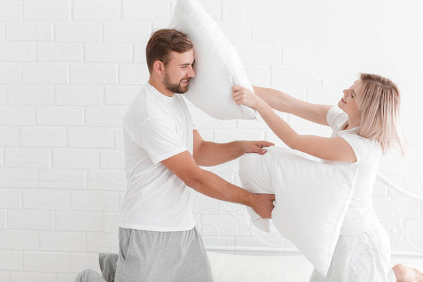 A young couple is beating pillows in the bedroom. - Foto, imagen