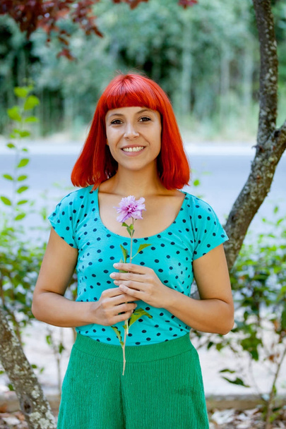 redhead young woman with flower  - Фото, зображення