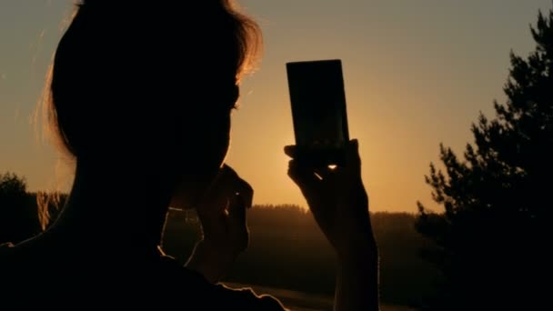 Silhouette donna scattare foto di tramonto con smartphone - Filmati, video