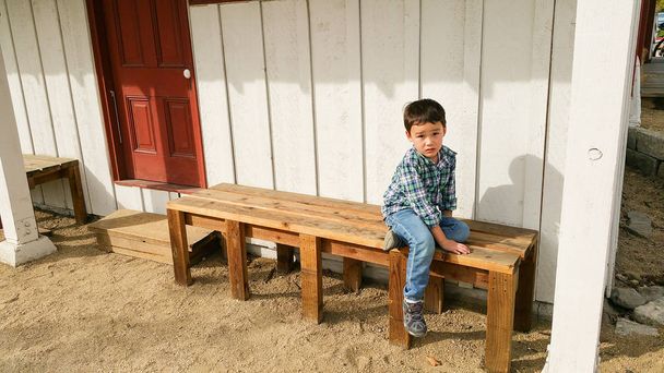 Χαριτωμένα μικρά κινέζικα και Καυκάσου αγόρι κάθεται στον πάγκο σε εξωτερικούς χώρους - Φωτογραφία, εικόνα