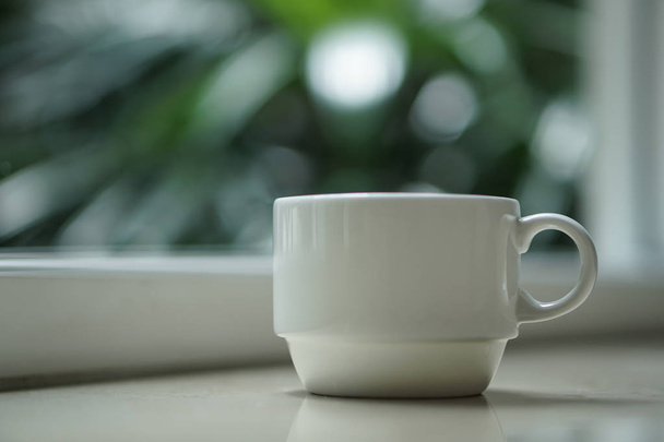 een kopje thee koffie bij het raam met uitzicht op de buiten - Foto, afbeelding