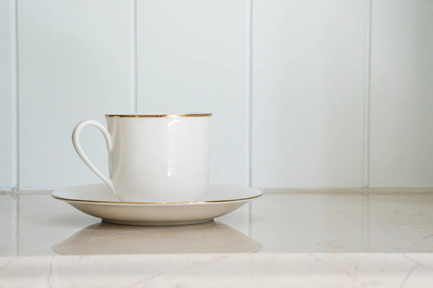 біла керамічна чашка з золотою смугою
  - Фото, зображення