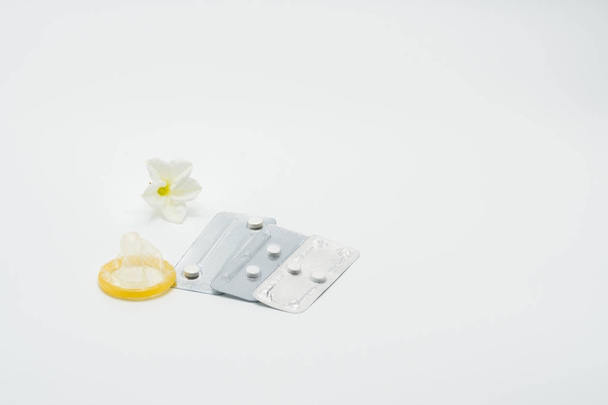 Три пузыря пакет экстренных контрацептивов таблетки с презервативом и цветок на белом фоне - Фото, изображение