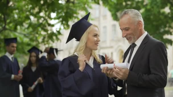 Gelukkig blond afgestudeerde student vreugde diploma met vader, graduatie ceremonie - Video