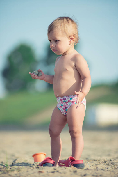 Cute baby playing with toys on sandy beach near the sea. - Fotografie, Obrázek