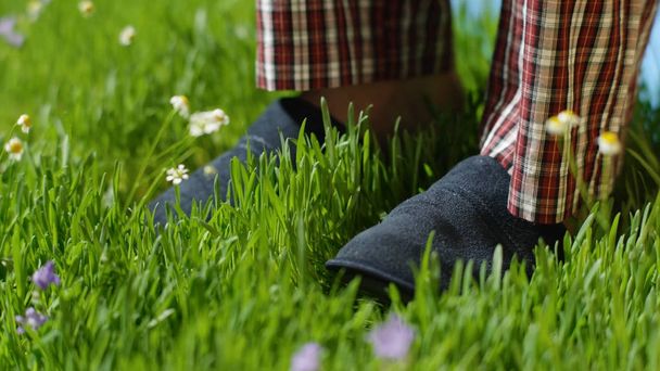 Man stands on the grass in Slippers. Male feet in sneakers on the grass - Photo, Image