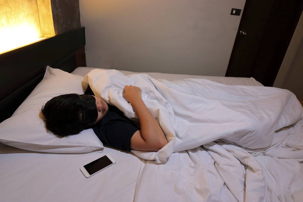 Plan grand angle de jeune homme asiatique confortable dormir avec masque sur le lit dans la chambre à coucher la nuit
 - Photo, image