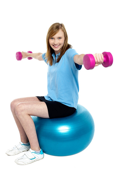 Girl sitting on pilates ball and doing dumbbells - Zdjęcie, obraz