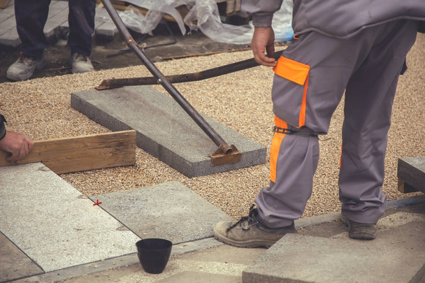 Trabalhadores do construtor colocar grandes lajes de pavimentação 2
 - Foto, Imagem
