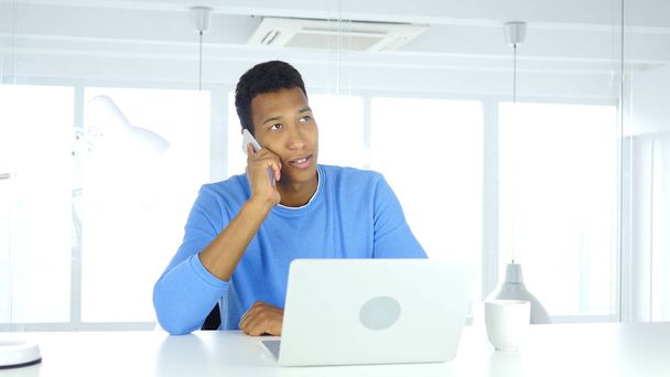 Afro-American Man Talking on Phone, Attending Call at Work - Photo, Image