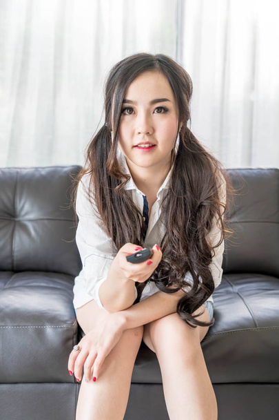 young asian woman changing tv channel at home in the living room - Foto, immagini