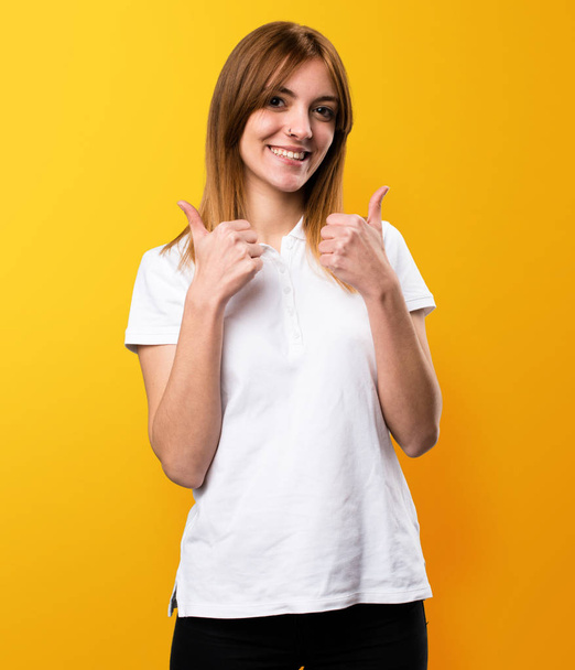 Beautiful young girl with thumb up on yellow background - Foto, imagen