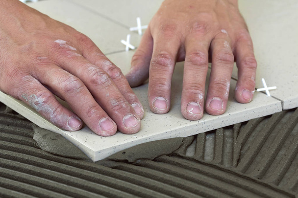 Робочі руки з керамічною плиткою та інструментами для плитки. Плитка для підлоги
 - Фото, зображення
