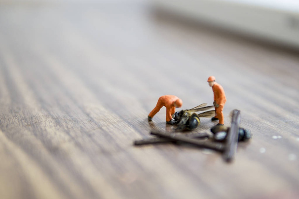 Miniature figure accident in workplace - Close up of construction workers try to lift up dead hornet accident concept with selective focus. - Photo, Image