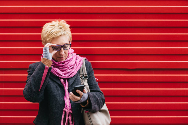Mulher adulta com smartphone na rua
 - Foto, Imagem