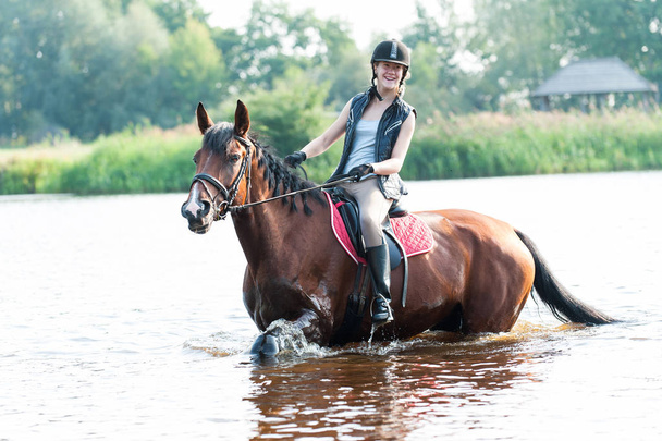 Smililng nuori teini tyttö ratsastus hevosen selässä joessa
 - Valokuva, kuva