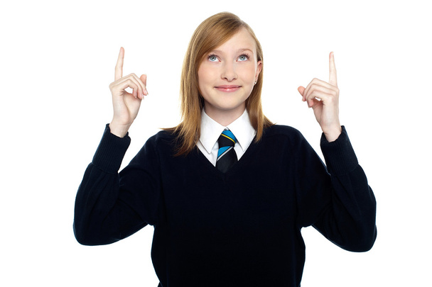 Amused schoolgirl looking and pointing upwards - Foto, Imagen