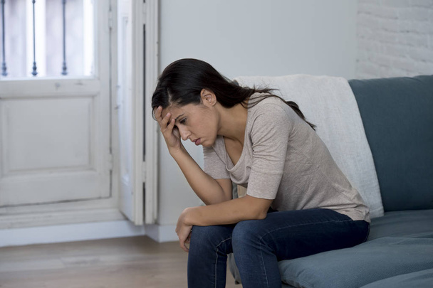  Латинська жінка лежить вдома, сидячи на дивані плаче стурбована стражданням депресії відчуваючи сум
 - Фото, зображення