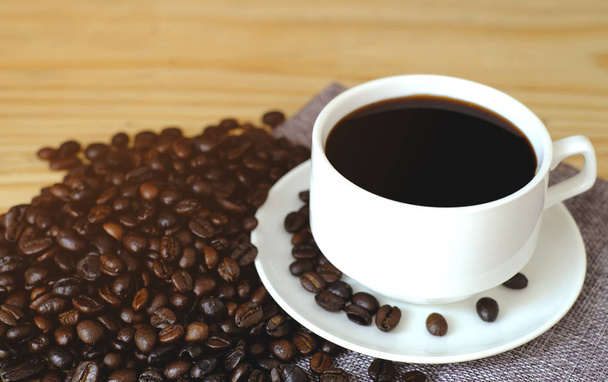 schwarzer Espresso mit Kaffeebohnen auf Holztisch - Foto, Bild