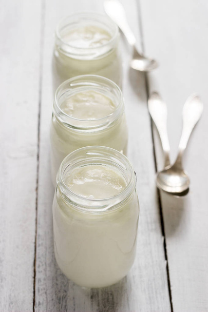 Homemade yogurt in a glass jar on a wooden table. Rustic style, selective focus. - Photo, Image