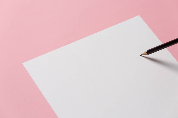 Blank Sheet Of Paper And Black Pencil On A Pink Background, Top View. Office Space Creativity Minimalism Concept - Foto, immagini