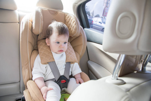 child in a baby car seat. Isofix clamping. beige car seat in a bright salon - Fotoğraf, Görsel