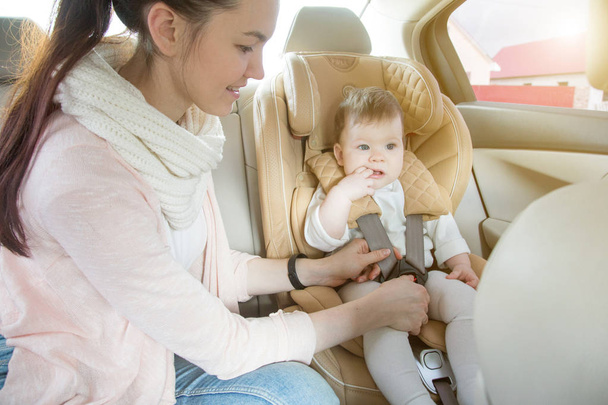 Mom fastens the child in the child seat - 写真・画像