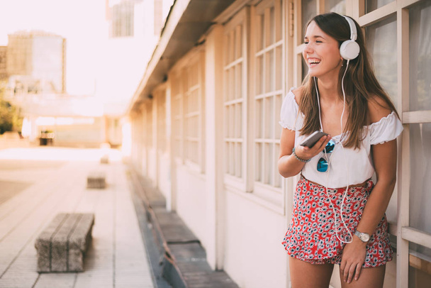 Счастливая молодая женщина слушает музыку по мобильному телефону
 - Фото, изображение