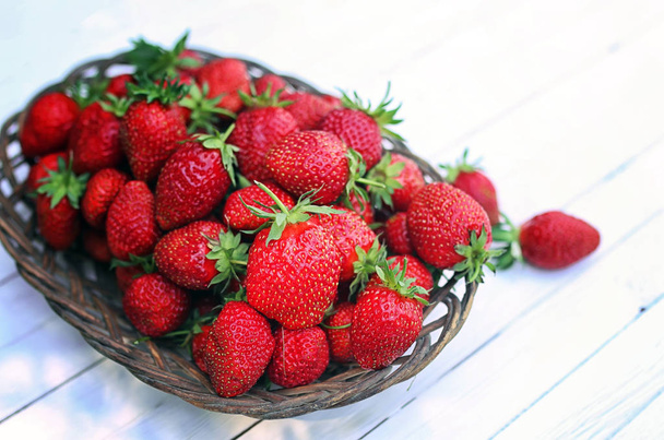 Strawberry in wicker plate on wooden background - Photo, Image