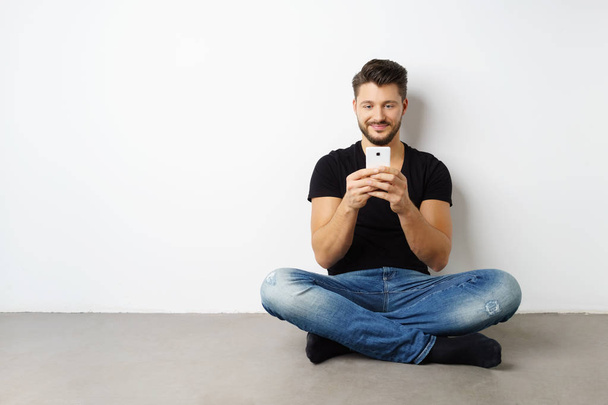 Young man sitting on floor with smartphone - Foto, Imagem