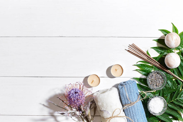 Курортный набор с морской солью, эфирным маслом, мылом и игрушкой, украшенный сухим цветом на белом деревянном фоне
 - Фото, изображение